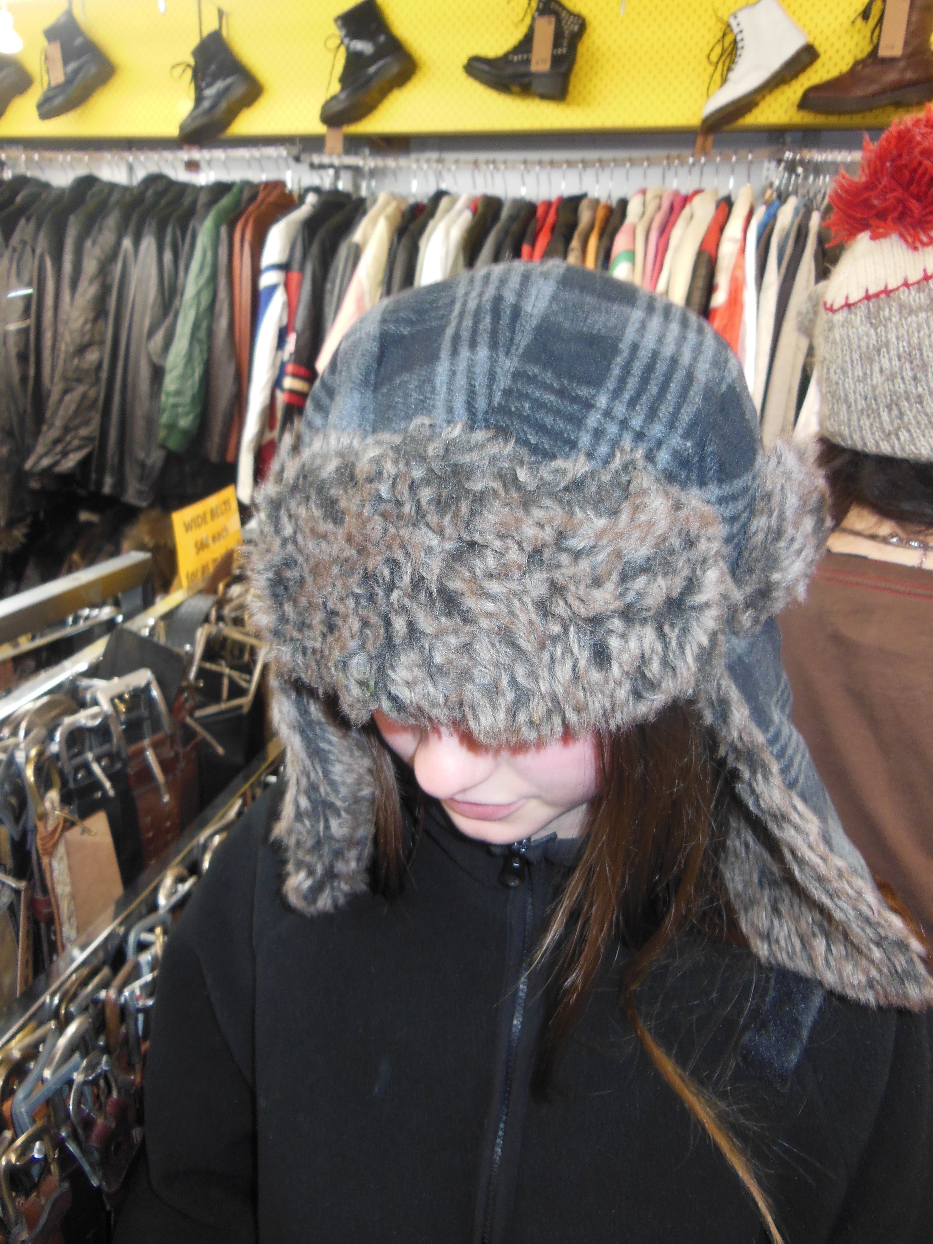 Front view of a person wearing a vintage dark grey plaid wool trapper hat with thick brown faux fur lining covering the forehead and ears.