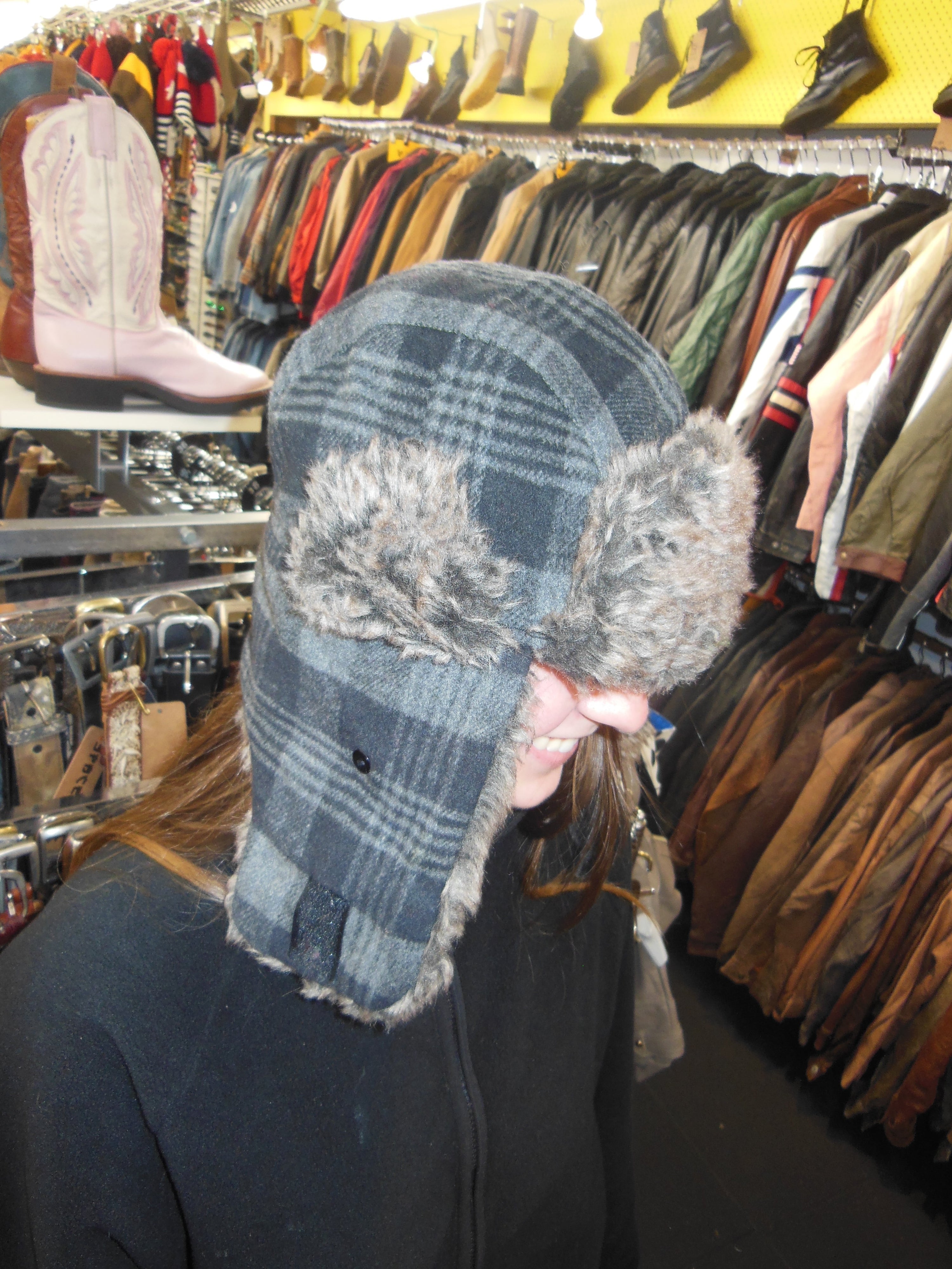 Side profile view of a vintage black and grey checkered aviator trapper hat showing the wool-blend exterior pattern and plush faux fur earflaps.
